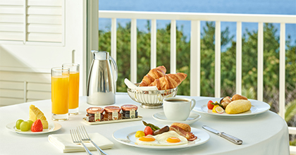 Image of room service breakfast on a table with an omelet, bread, coffee, orange juice, and fruit.